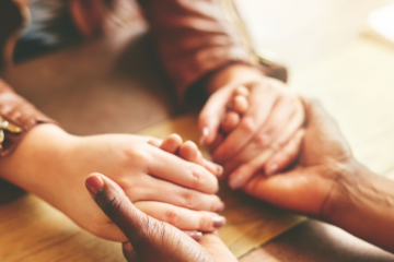 two people holding hands across a table.