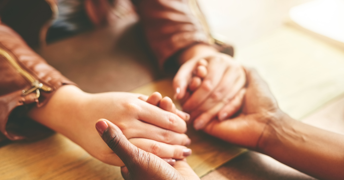 two people holding hands across a table.