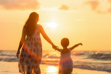 Mothers and Mother’s Day - Mother and child walking on the beach holding hands at sunset