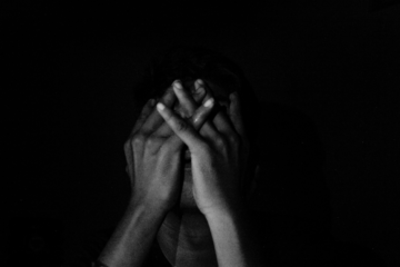 Why Me, God? Finding Purpose in the Pain - CBCC Blog Post Cover Image showing person in darkness clasping their hands over their face