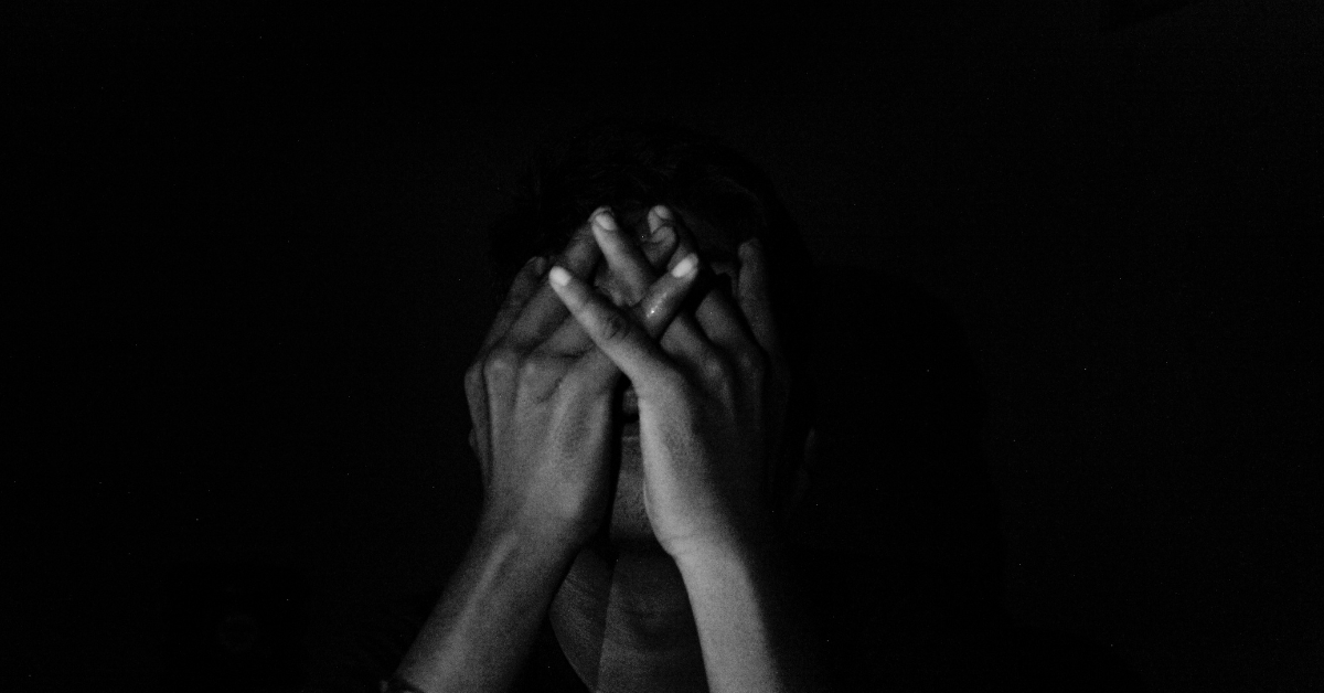 Why Me, God? Finding Purpose in the Pain - CBCC Blog Post Cover Image showing person in darkness clasping their hands over their face